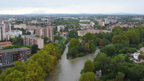 Flooded-river-Montpellier-aerial-shot-along-buildings-France-cloudy-rainy-day